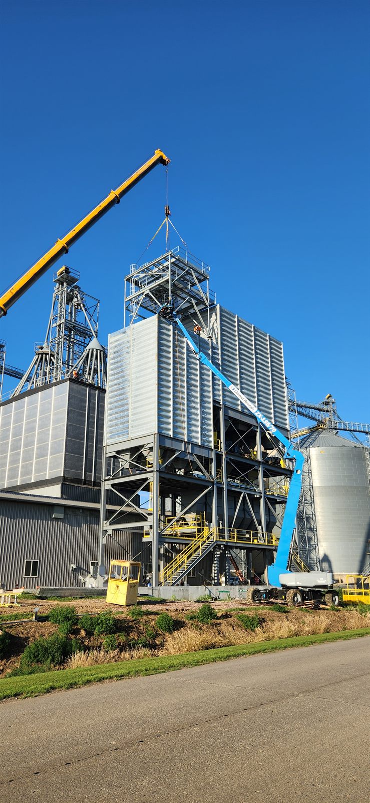 Crane and boom lift erecting a grain storage facility